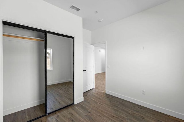 unfurnished bedroom with dark hardwood / wood-style floors and a closet