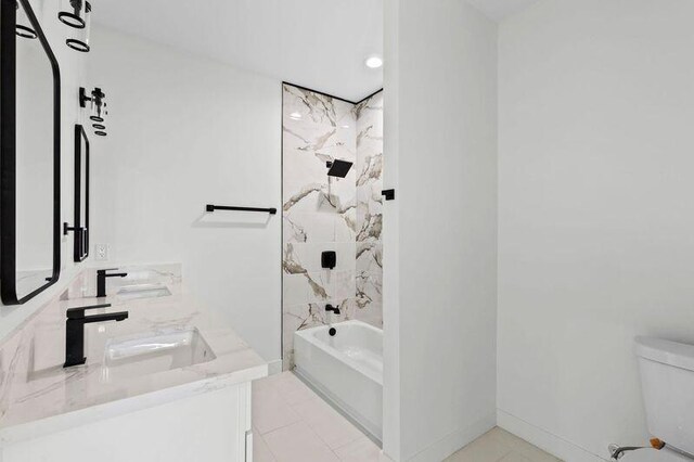 full bathroom with tile patterned flooring, vanity, tiled shower / bath combo, and toilet