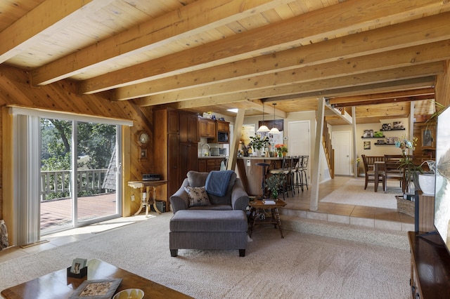 carpeted living room featuring beamed ceiling and wood walls