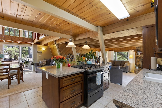 kitchen featuring beam ceiling, light tile patterned floors, decorative light fixtures, and stainless steel range with gas cooktop