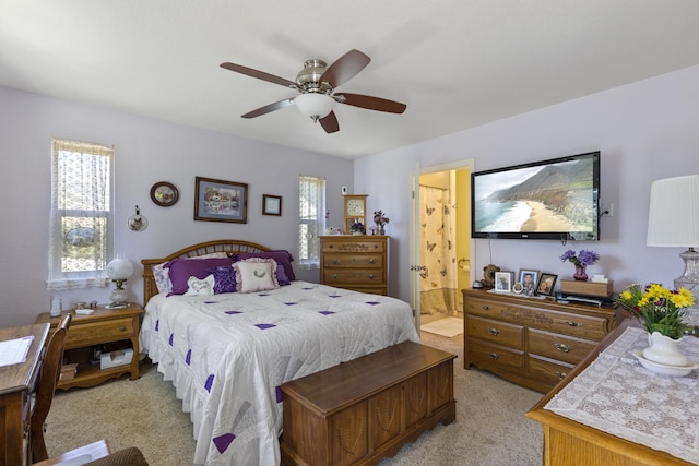 carpeted bedroom featuring multiple windows, connected bathroom, and ceiling fan