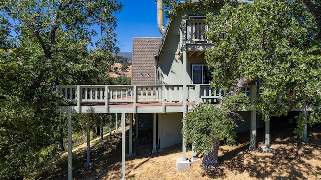 back of property with a wooden deck and a balcony