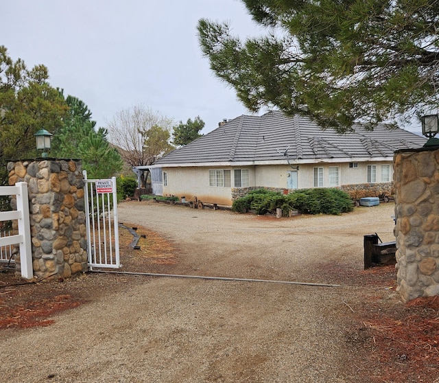 view of home's exterior with stucco siding, a tile roof, driveway, and a gate