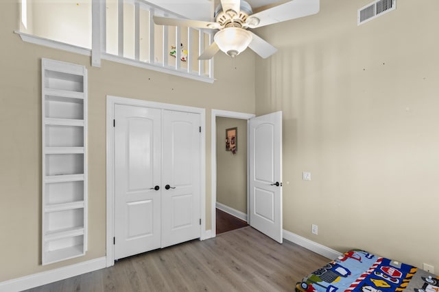23600 Dart Dr, Tehachapi, CA 93561 - unfurnished bedroom featuring a high ceiling, wood finished floors, baseboards, a closet, and a ceiling fan