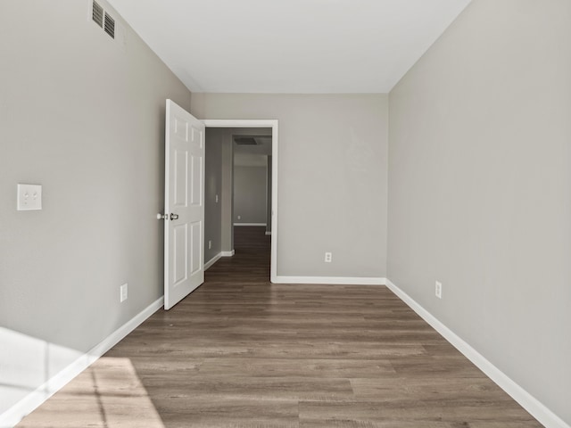 unfurnished room featuring dark wood finished floors, visible vents, and baseboards