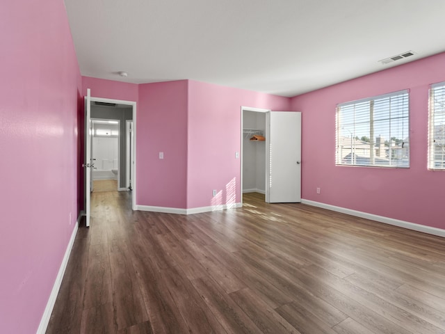 unfurnished bedroom with wood finished floors, visible vents, and baseboards