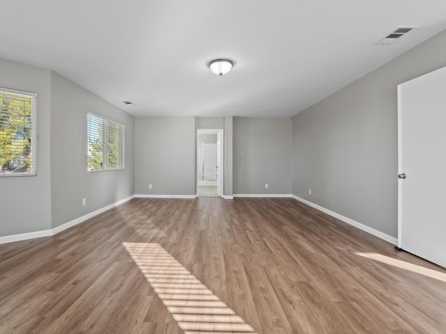 interior space featuring visible vents, connected bathroom, baseboards, and wood finished floors