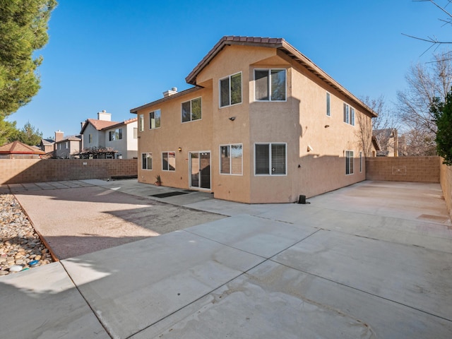 back of house featuring a fenced backyard, a patio, and stucco siding