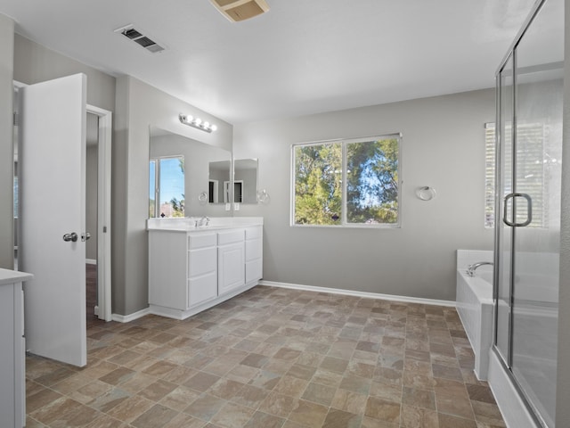 bathroom featuring a bath, baseboards, visible vents, and a healthy amount of sunlight