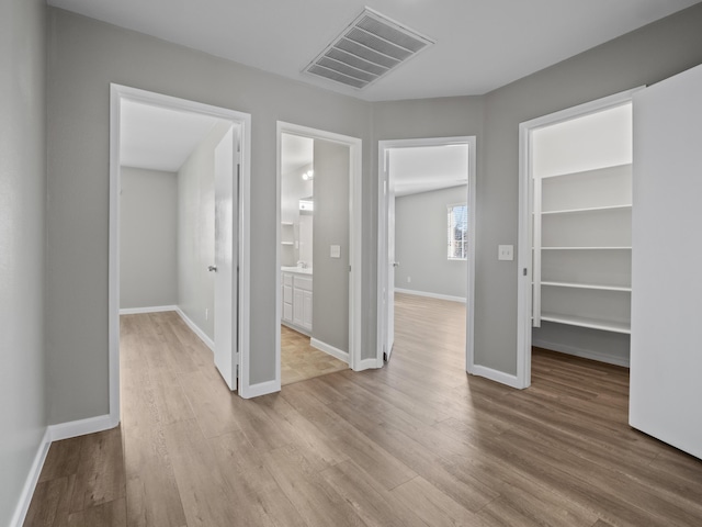 interior space featuring light wood-type flooring, visible vents, and baseboards