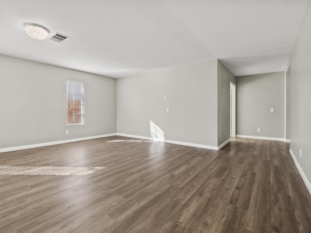 spare room featuring dark wood finished floors, visible vents, and baseboards