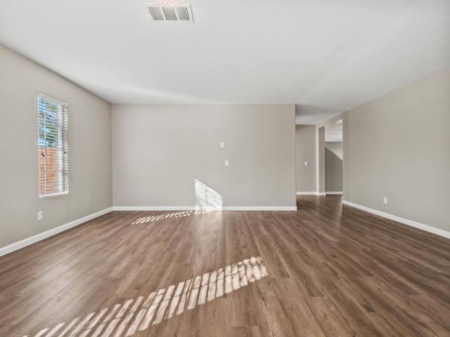 spare room featuring wood finished floors, visible vents, and baseboards