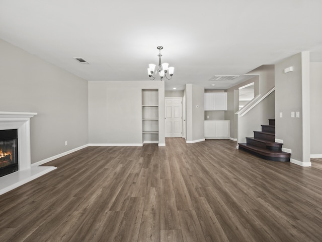 unfurnished living room featuring dark wood-style floors, stairs, visible vents, and a glass covered fireplace