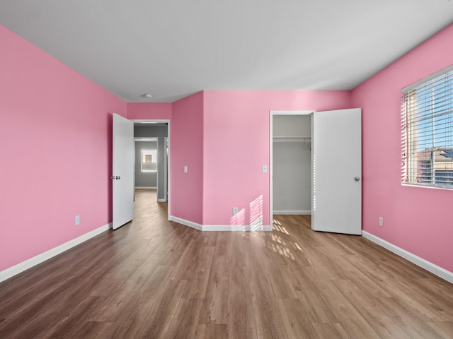 unfurnished bedroom with a closet, wood finished floors, and baseboards