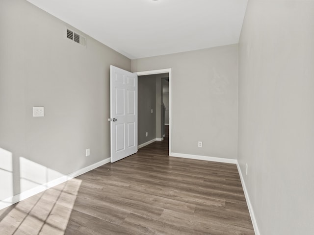 unfurnished room featuring visible vents, baseboards, and wood finished floors