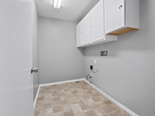 clothes washing area featuring gas dryer hookup, hookup for a washing machine, baseboards, cabinet space, and stone finish floor