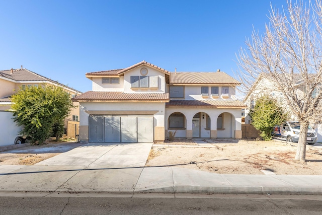 mediterranean / spanish home with concrete driveway, stucco siding, a tile roof, and fence