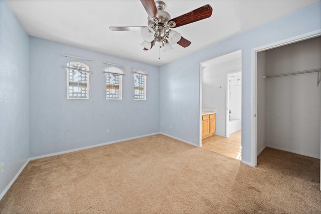 unfurnished bedroom with light carpet, baseboards, ensuite bath, ceiling fan, and a closet