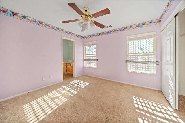 unfurnished bedroom featuring ensuite bathroom, ceiling fan, carpet floors, visible vents, and baseboards