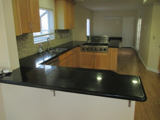 kitchen with dark countertops, a peninsula, a sink, and light wood finished floors