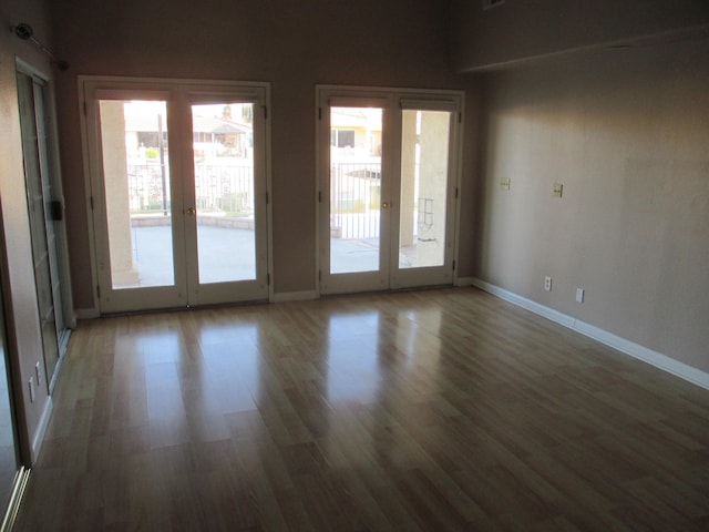 empty room with baseboards, wood finished floors, and french doors