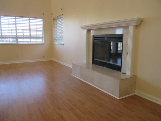unfurnished living room with baseboards, a fireplace, and wood finished floors