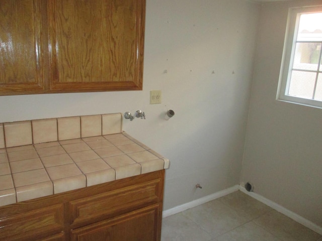 laundry area featuring baseboards, cabinet space, tile patterned flooring, and hookup for a gas dryer