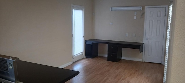 unfurnished office featuring baseboards and wood finished floors
