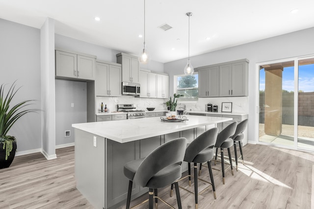 kitchen with gray cabinetry, pendant lighting, a kitchen island, and stainless steel appliances