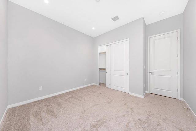 unfurnished bedroom with light carpet and a closet