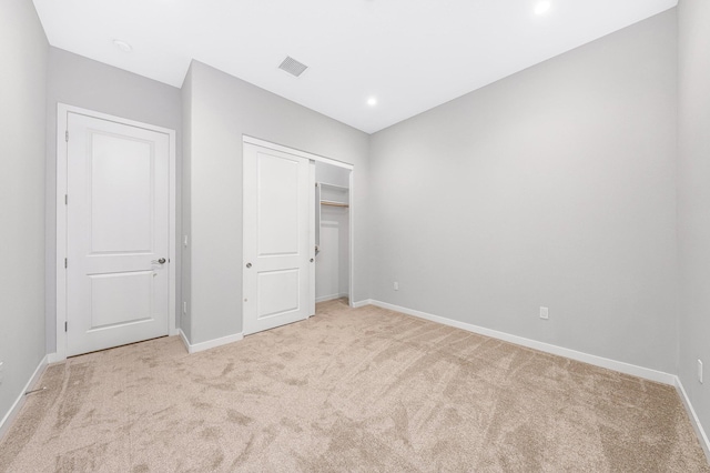 unfurnished bedroom with light carpet and a closet