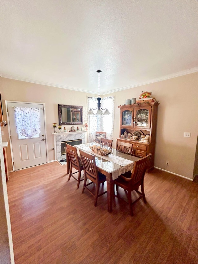 dining area with dark hardwood / wood-style floors, ornamental molding, a fireplace, and an inviting chandelier