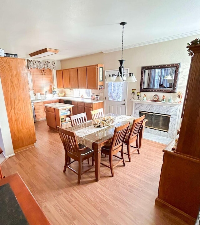 dining room with crown molding, a premium fireplace, sink, and light hardwood / wood-style floors