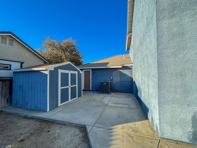 view of patio featuring central AC unit and a storage shed