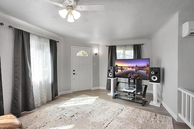 foyer entrance with ceiling fan, light hardwood / wood-style floors, and a wall unit AC