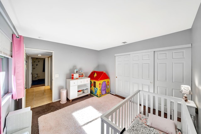 bedroom featuring a nursery area, a closet, and dark carpet