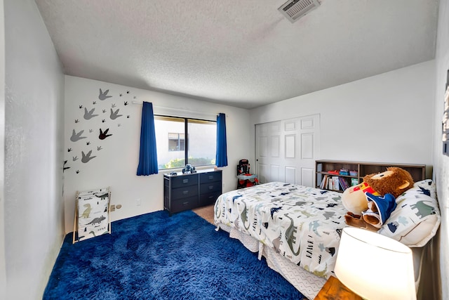 bedroom with a textured ceiling, a closet, and dark carpet