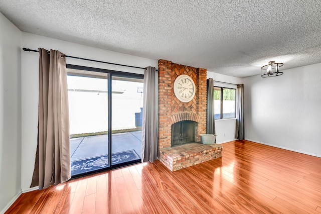 unfurnished living room featuring wood-type flooring, a fireplace, and a textured ceiling