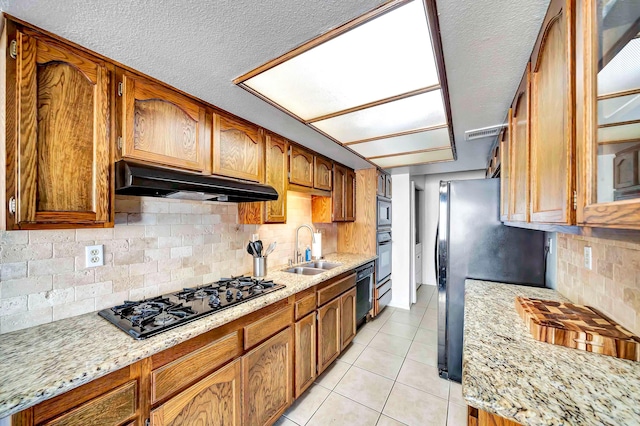 kitchen featuring backsplash, black appliances, sink, light stone countertops, and light tile patterned floors