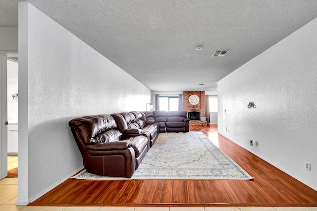 living room featuring a textured ceiling, light tile patterned floors, and a fireplace