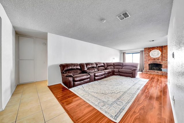 tiled living room featuring a textured ceiling and a brick fireplace