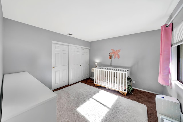 carpeted bedroom with a closet and a crib