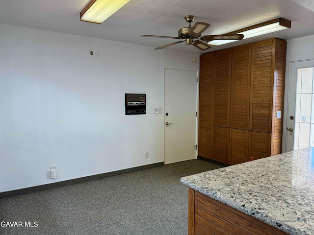 28714 Cruthers Creek Rd, Pearblossom, CA 93553 - kitchen featuring a ceiling fan, dark colored carpet, a textured ceiling, and brown cabinets