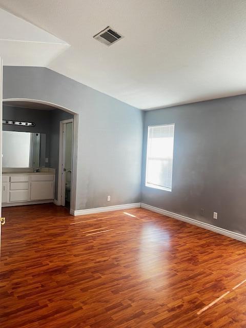 unfurnished room featuring hardwood / wood-style flooring, lofted ceiling, and sink