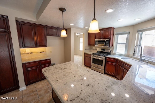4722 Sungate Dr, Palmdale, CA 93551 - kitchen with stainless steel appliances, plenty of natural light, light stone countertops, decorative light fixtures, and a textured ceiling