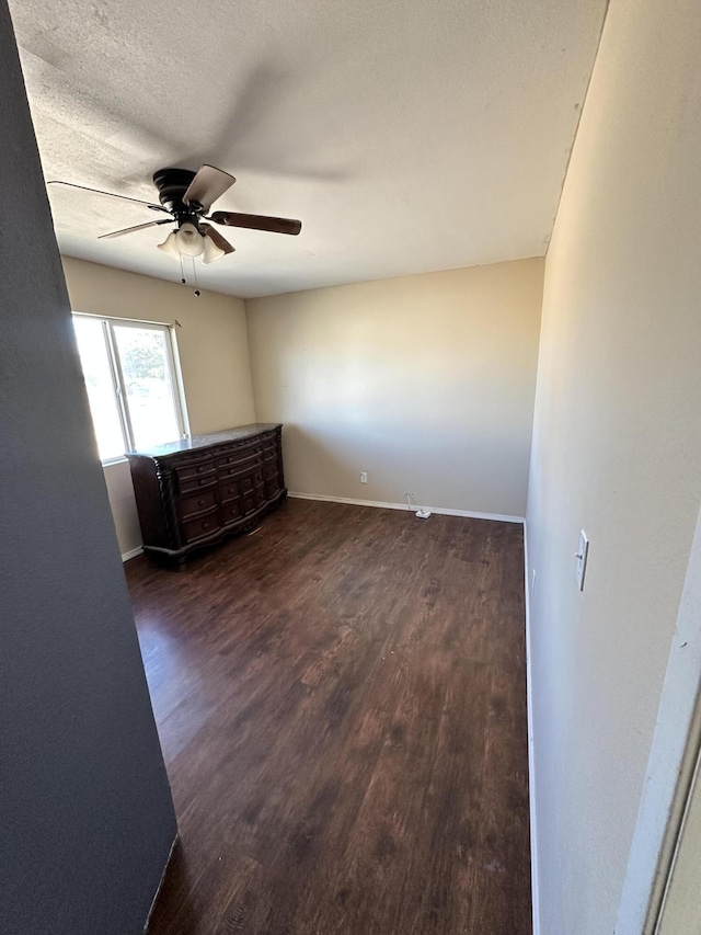 spare room with dark hardwood / wood-style floors, ceiling fan, and a textured ceiling