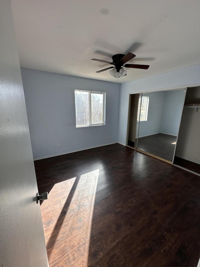 unfurnished bedroom with ceiling fan, dark hardwood / wood-style floors, a closet, and multiple windows