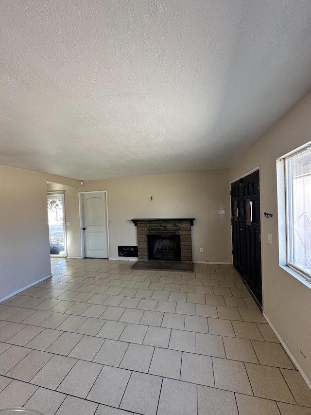 unfurnished living room with a textured ceiling, plenty of natural light, light tile patterned floors, and a fireplace