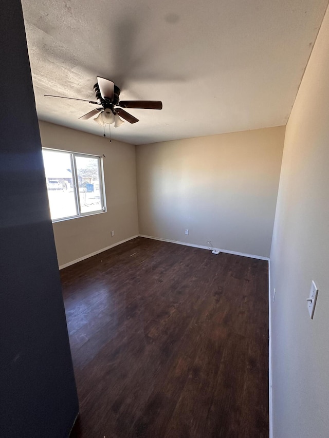 unfurnished room with ceiling fan and dark wood-type flooring