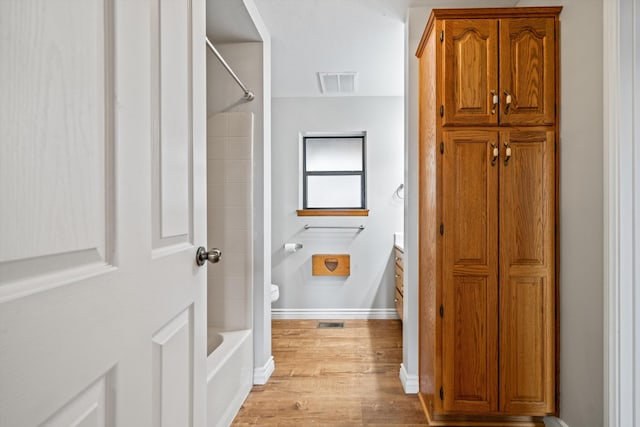 bathroom with toilet, hardwood / wood-style floors, and shower / bathing tub combination